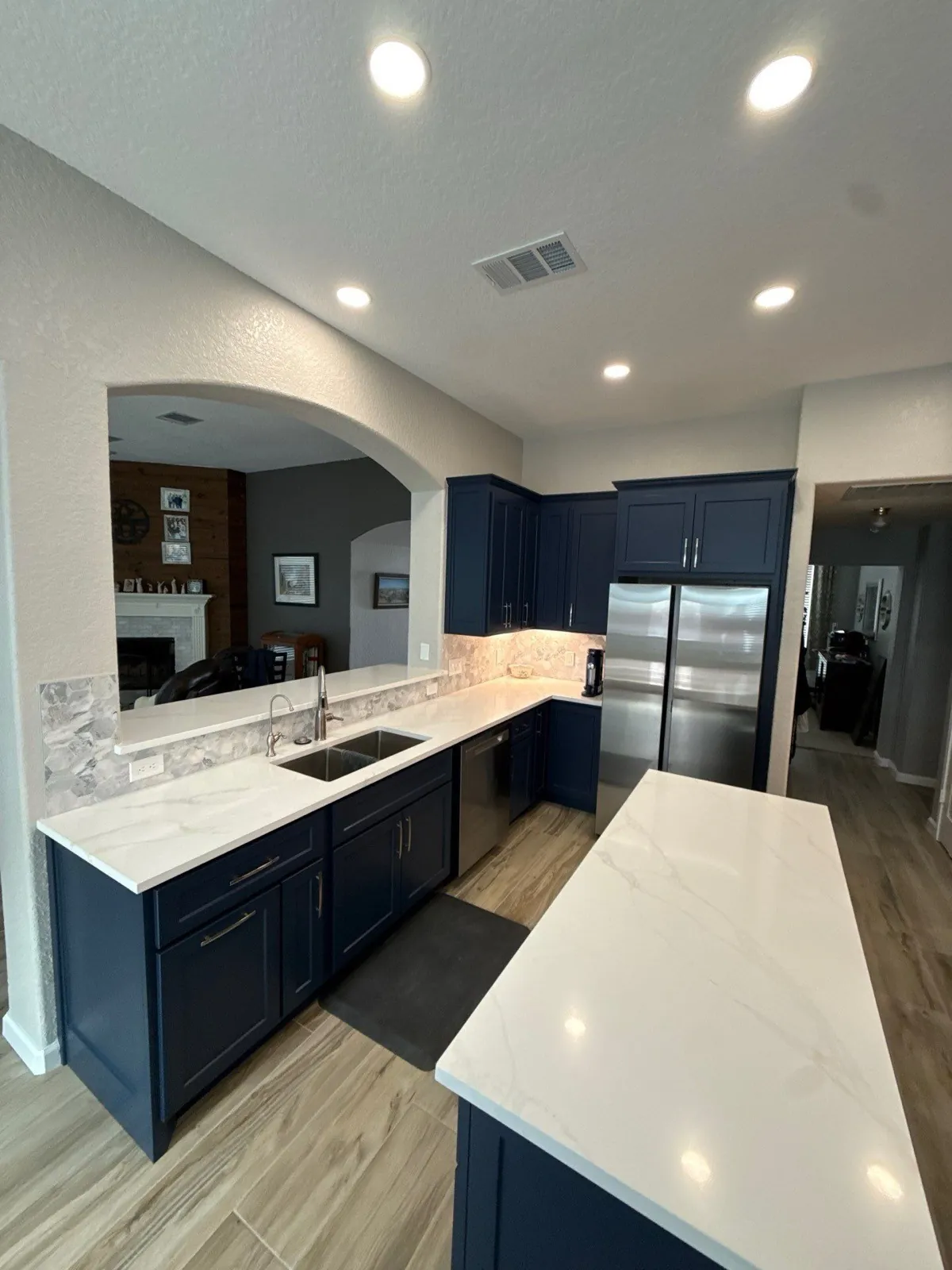 Kitchen after the remodel — navy cabinets, quartz counters, wood-look floors